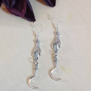 Hand holding Silver Sickle Dangling Earrings, with nickel free and hypoallergenic backs of your choice, scythe earrings