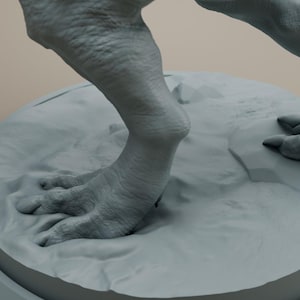 Puede incluir: Primer plano de los pies y las piernas de una figura de dinosaurio gris. La figura est&aacute; de pie sobre una base redonda gris.