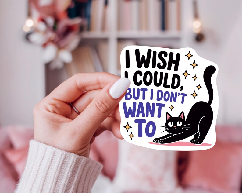 K&ouml;nnte beinhalten: Wei&szlig;er Aufkleber mit dem Text &bdquo;I wish I could, but I don't want to&ldquo; und einer Illustration einer schwarzen Katze. Die Katze streckt sich mit erhobenem Schwanz. Goldene Sterne umgeben Text und Katze.