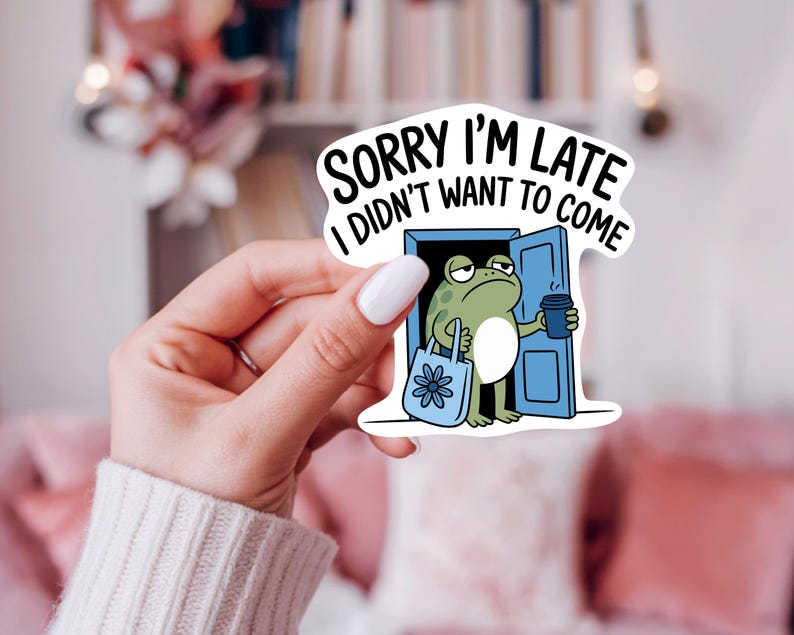 K&ouml;nnte beinhalten: Ein wei&szlig;er Aufkleber mit dem Text "SORRY I'M LATE I DIDN'T WANT TO COME". Der Aufkleber zeigt einen Cartoon-Frosch, der eine Kaffeetasse und eine Tragetasche h&auml;lt und in einer blauen T&uuml;r steht. Der Frosch ist gr&uuml;n und hat einen m&uuml;rrischen Gesichtsausdruck.