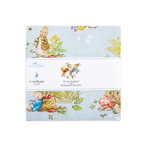 May include: A stack of light blue fabric squares featuring illustrations of Peter Rabbit and Benjamin Bunny. The fabric has a repeating pattern of the characters and floral elements. The product is labeled "Peter Rabbit and Benjamin Bunny."
