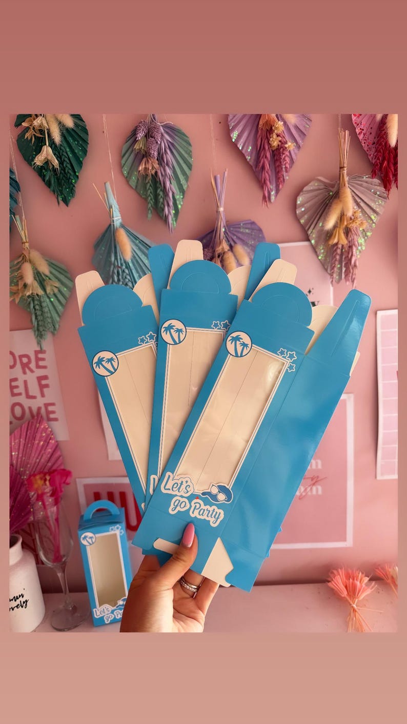 May include: A set of four blue cardboard boxes with a window and a handle. The boxes have a palm tree design and the text "Let's go Party".
