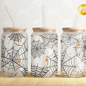 Puede incluir: Tres vasos blancos con telara&ntilde;as negras y ara&ntilde;as naranjas y moradas impresas en ellos. Cada vaso tiene una pajita de pl&aacute;stico transparente.