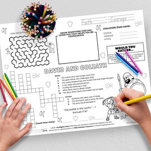 May include: A children's activity sheet with the text "David and Goliath" features a maze, crossword, and drawing prompt. Colored pencils and crayons are scattered around the sheet. A hand is drawing with a yellow pencil.