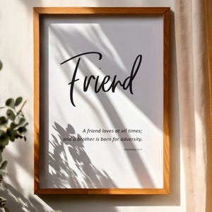 May include: Wooden framed print with the word "Friend" in elegant script. The print includes the quote "A friend loves at all times; and a brother is born for adversity." from Proverbs 17:17. The frame is a warm, natural wood tone.