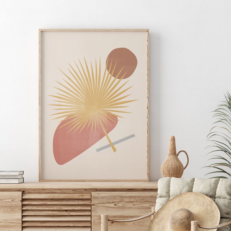 May include: A minimalist art print featuring a stylised palm leaf in shades of gold and brown, with abstract shapes in shades of pink and grey on a cream background.