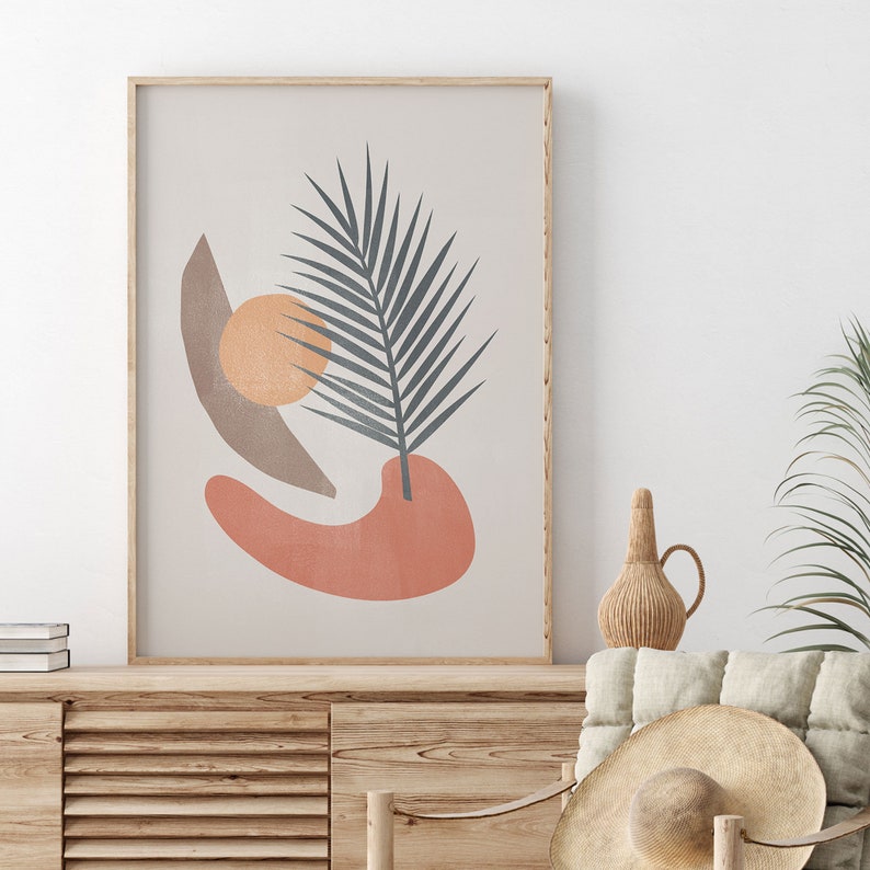 K&ouml;nnte beinhalten: Ein gerahmter Druck mit einem abstrakten Design, das ein stilisiertes Palmblatt, einen pfirsichfarbenen Kreis und eine braune Sichelform auf einem beigefarbenen Hintergrund zeigt.