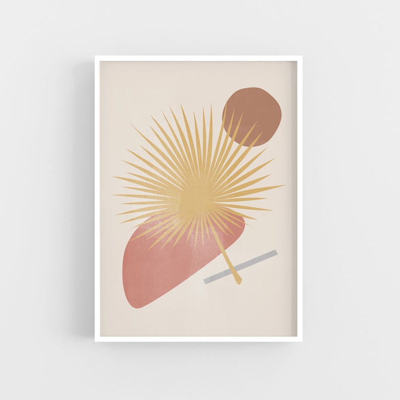 May include: Abstract art print featuring a stylised palm leaf in shades of yellow and gold, a brown circle, and a pink and red shape. The print is framed in a white frame.