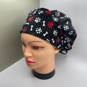 May include: Black scrub hat with a white and red paw print and bone pattern.