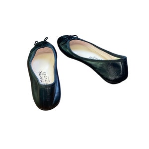 May include: Pair of black leather ballet flats with a small bow detail on the toe. The flats are made by Mayer  &  Stid, and are made in Italy.