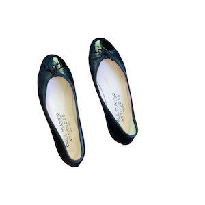 May include: A pair of black leather ballet flats with a patent leather toe. The flats have a bow on the toe and the words "Paul Mayer Attitudes" are printed on the insole.