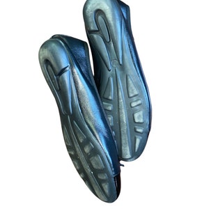 May include: A pair of black leather flats with a rubber sole. The shoes are worn and have some scuffs on the soles.