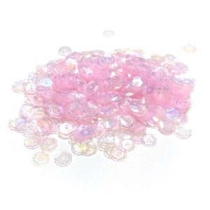May include: A pile of iridescent pink sequins, perfect for crafting and embellishing projects.