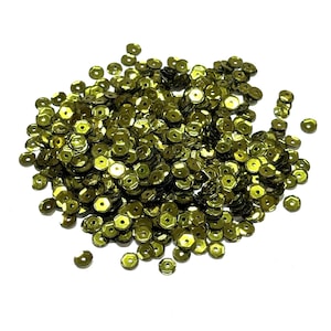 May include: A large collection of small, round, olive green sequins. Each individual sequin features a flat, reflective surface with a single, centered hole for attachment. The sequins are scattered in a loose pile, displaying a metallic finish.