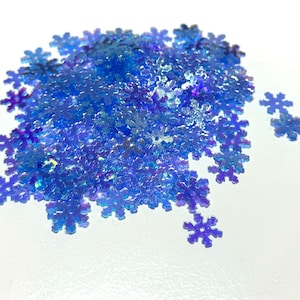 May include: A pile of iridescent blue snowflake-shaped glitter. The glitter is perfect for adding a touch of sparkle to crafts, decorations, and more.
