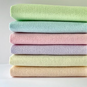 May include: A stack of six pastel colored fleece fabric squares. The colors are light green, light blue, pink, lavender, light yellow, and peach.