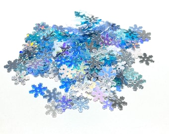 May include: A pile of iridescent blue and silver snowflake-shaped glitter. The glitter is perfect for adding a touch of sparkle to crafts, cards, and other projects.