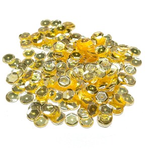 May include: A large pile of gold-colored sequins, perfect for crafting and embellishing projects.