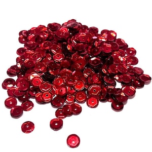 May include: A pile of red sequins, a popular craft supply for embellishing clothing, accessories, and home decor projects.