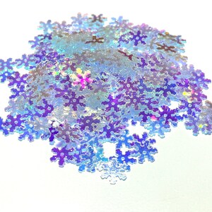 May include: A pile of iridescent blue snowflake glitter. The glitter is perfect for adding a touch of sparkle to crafts, decorations, and more.