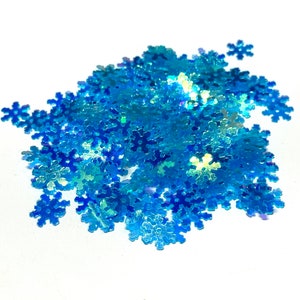 May include: A pile of iridescent blue snowflake glitter. The glitter is perfect for adding a touch of sparkle to crafts, cards, and other projects.