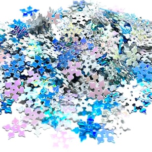 May include: A pile of iridescent snowflake-shaped glitter in shades of blue, white, and purple.