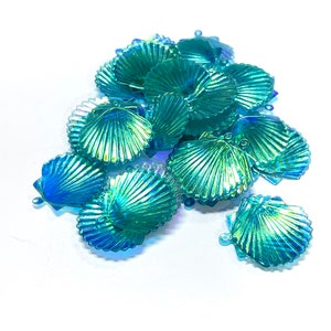 May include: A pile of iridescent blue and green plastic seashells with a scalloped edge. The shells have a shiny, reflective finish.