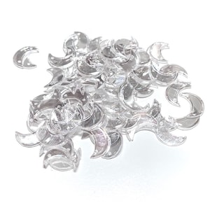 May include: A pile of clear plastic crescent moon shaped embellishments.