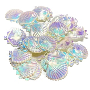 May include: A pile of iridescent white plastic seashells with a scalloped edge. The shells have a pearlescent finish and are perfect for crafting.