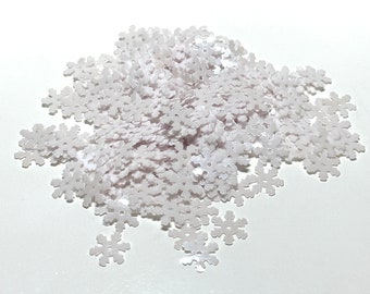 May include: A pile of white snowflake-shaped sequins. The sequins are made of a shiny, iridescent material.