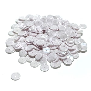 May include: A pile of white iridescent sequins, perfect for crafting and embellishing projects.