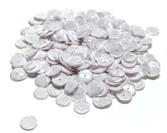 May include: A pile of white iridescent sequins, perfect for crafting and embellishing projects.