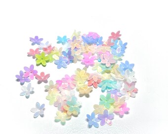 Op de afbeelding: Een strooiing van pastelkleurige bloemvormige pailletten, in tinten roze, blauw, geel en groen.