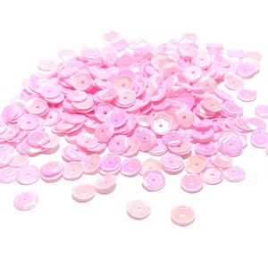 May include: A pile of iridescent pink sequins, perfect for crafting and decorating.