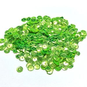 May include: A large pile of lime green sequins. The sequins are round and have a shiny finish.