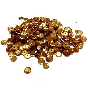 May include: A pile of gold-colored sequins, perfect for crafting and decorating.