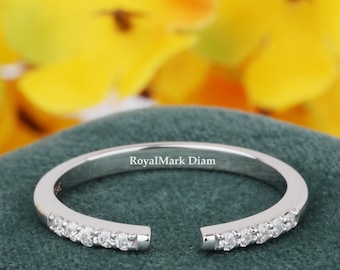 May include: A silver-toned open band ring featuring a row of small, clear, round-cut stones set along each side of the opening. The interior of the band is engraved with the text RoyalMark Diam in a clear, sans-serif font.