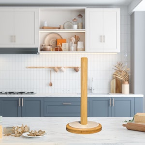 May include: A wooden paper towel holder with a white base. The holder is standing on a white countertop in a kitchen setting.