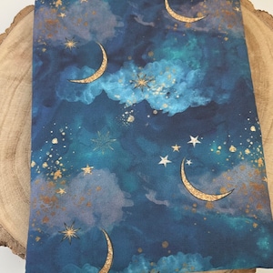 A dark blue book sleeve with a celestial design featuring gold  coloured crescent moons, stars, and clouds. The sleeve holds a book. The book sleeve is made of fabric.