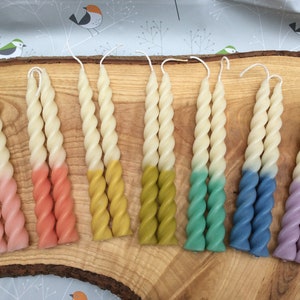 May include: A set of ten twisted candles with an ombre colour effect. The candles are white at the top and fade to pink, orange, yellow, green, blue, and purple.
