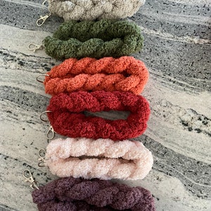 May include: Six braided keychains in various colors, including gray, green, orange, red, pink, and purple. Each keychain has a silver metal clasp.
