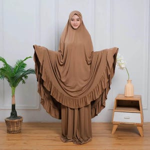 May include: A brown maxi dress with a ruffled hem and matching headscarf. The dress has a loose, flowing fit and is made of a soft, comfortable fabric.