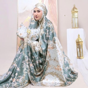 May include: A matching set of prayer garments, including a head covering, shawl, and handbag, in a sage green and cream floral pattern. The set features ornate gold detailing and is made of a silky fabric. The text "JUNGKELBOY" is visible.