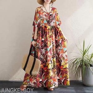 May include: A long, flowing dress with a vibrant floral pattern in shades of red, orange, yellow, and blue. The dress has short sleeves and a V-neck. A straw tote bag with black straps is held in the hand. The text "JUNGKELBOY" is visible at the bottom.