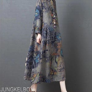 May include: A long-sleeved dress with a button-down front and a distinctive print in grey, blue, and orange hues. The dress has a collared neckline and a flowing, A-line shape. The text "JUNGKELBOY" is visible at the bottom of the image.