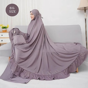 May include: A lilac prayer garment and matching head covering. The garment has a ruffled hem. The image includes a circular graphic with the text "BIG SIZE". The person is seated on a gray sofa.