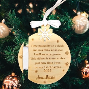 May include: A wooden Christmas ornament with a white ribbon and the text "Time passes by so quickly and in a blink of an eye I will soon be grown. This ribbon is to remember just how little I was on my 1st christmas 2024 Ava Marie".