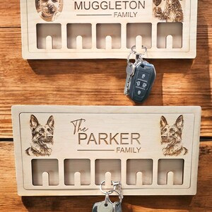 May include: A wooden key holder with five hooks. The top of the key holder has a personalised inscription that reads "The Muggleton Family" and a photo of a dog. The bottom of the key holder has a personalised inscription that reads "The Parker Family" and a photo of a dog.