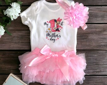 May include: A pink tutu with a white bodysuit featuring a Minnie Mouse graphic and the text "My 1st Mother's Day".