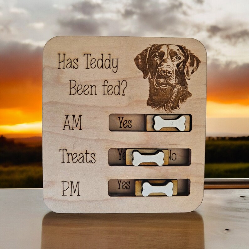 May include: Wooden sign with a black Labrador Retriever image and the text "Has Teddy Been Fed?" with sliding bone toggles for AM, Treats, and PM.